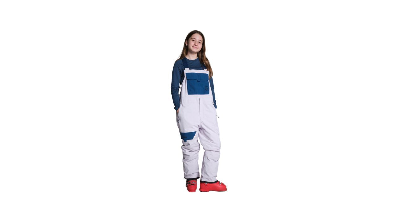  A young girl in a blue and white snow suit, enjoying a snowy outdoor activity.